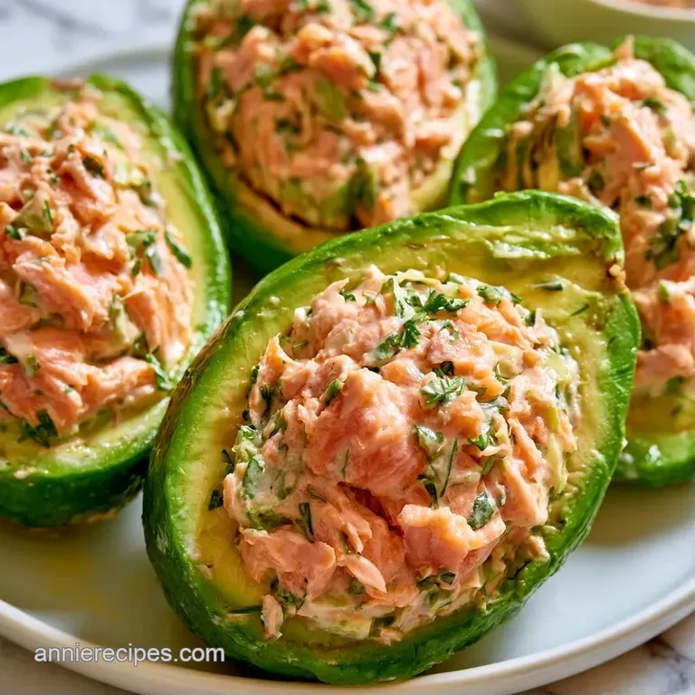 Two vibrant green avocado halves filled with creamy pink salmon, garnished with microgreens on a dark slate platter.